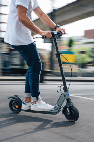 un homme roulant sur une trottinette électrique micro merlin II