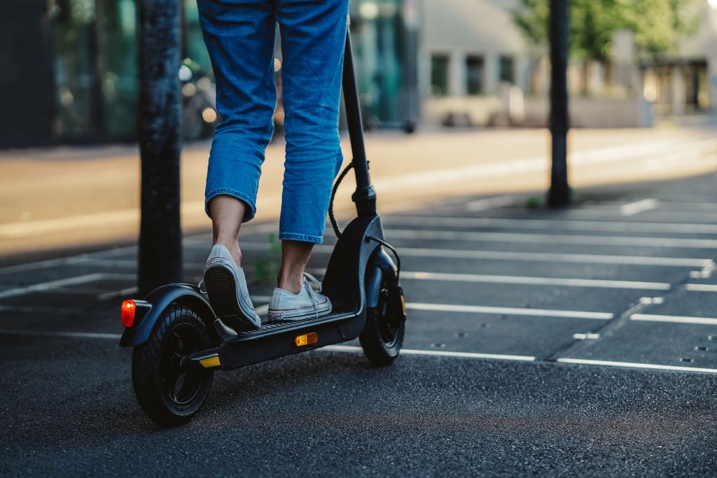 gros plan sur les jambes d'une personne qui est sur une trottinette électrique en ville